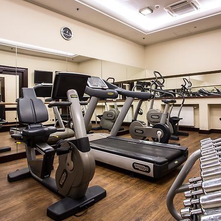 فندق راديسون بلو، غدانسك المظهر الخارجي الصورة The photo displays a small gym or fitness room. The room features various exercise equipment, including a treadmill, an elliptical machine, and a set of dumbbells arranged on a rack. There are mirrors on the wall, which help create a sense of space a