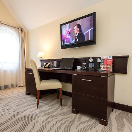 فندق راديسون بلو، غدانسك المظهر الخارجي الصورة The photo depicts a corner of a room featuring a stylish desk with a chair and a television mounted on the wall above. The desk has various items on it, possibly including a telephone, clock, and some decorative elements or stationery. There is a lam