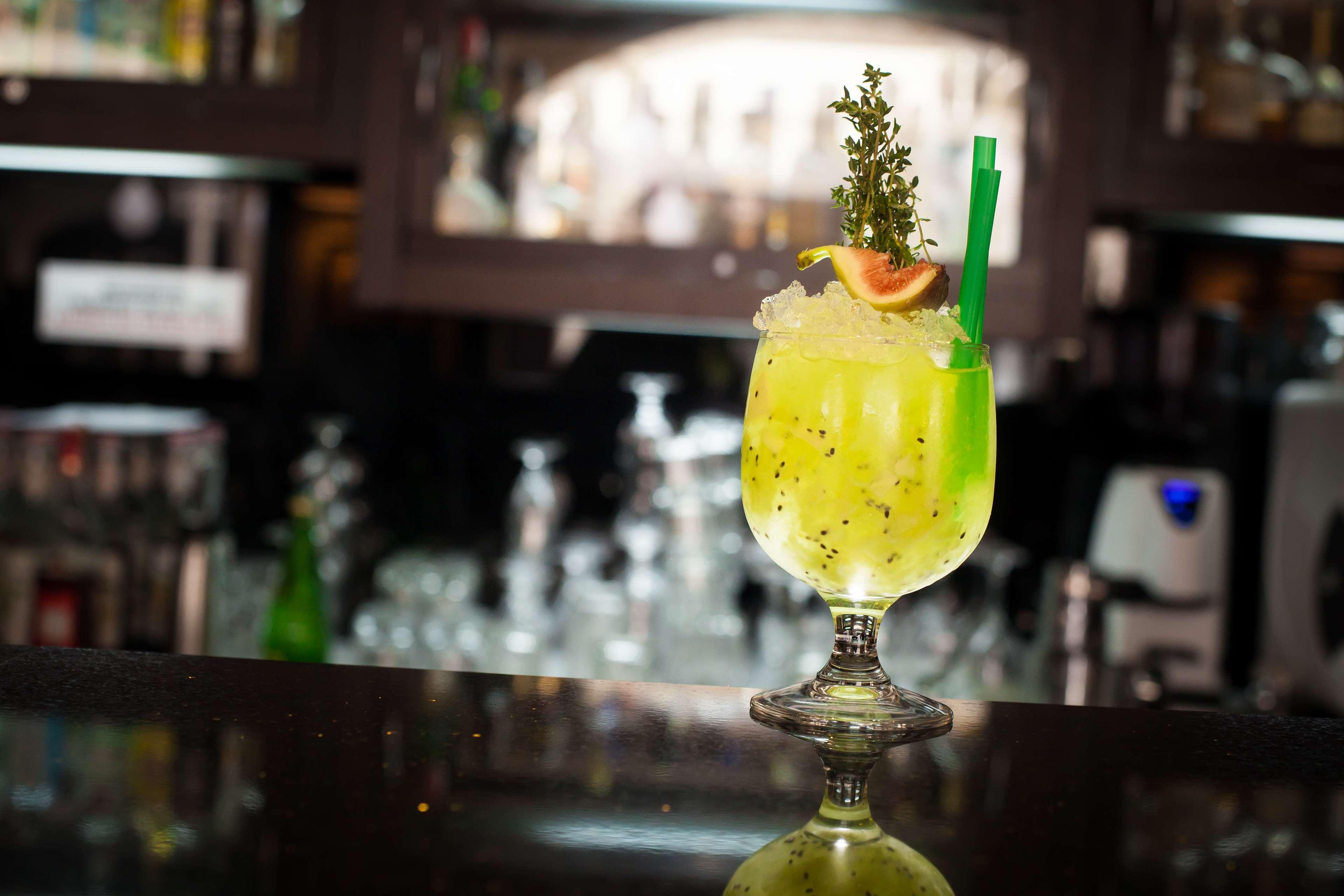 فندق راديسون بلو، غدانسك المظهر الخارجي الصورة The photo shows a vibrant, green cocktail served in a stylish glass with a wide base and an elegant stem. The drink is garnished with a slice of fruit and a sprig of herbs, adding visual appeal. A green straw is inserted into the drink, and it appear