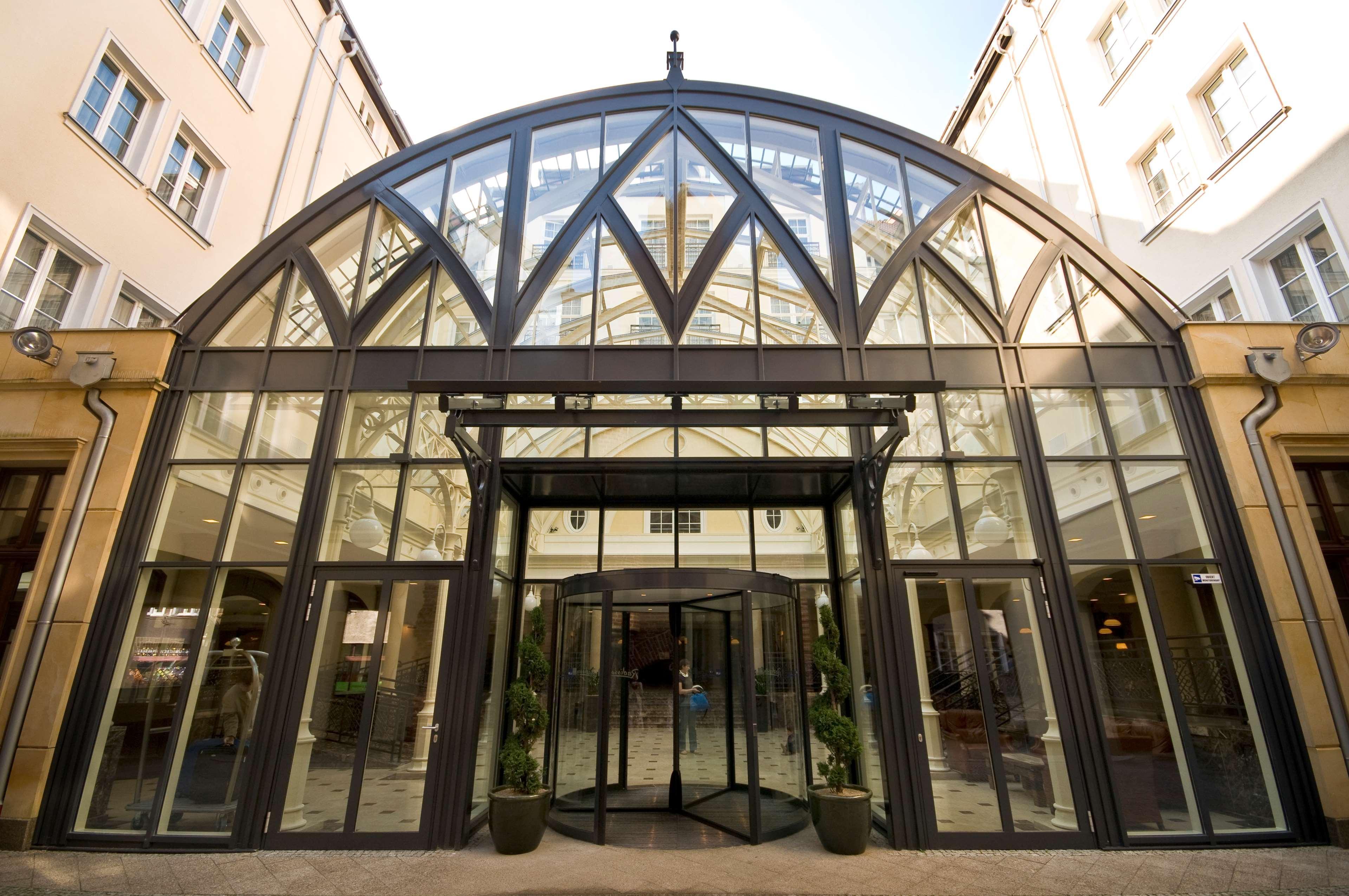 فندق راديسون بلو، غدانسك المظهر الخارجي الصورة The photo shows a modern glass entrance, featuring a large, arched roof structure. The facade is predominantly made of glass and metal, allowing natural light to illuminate the interior. There are revolving doors at the center, flanked by symmetrical