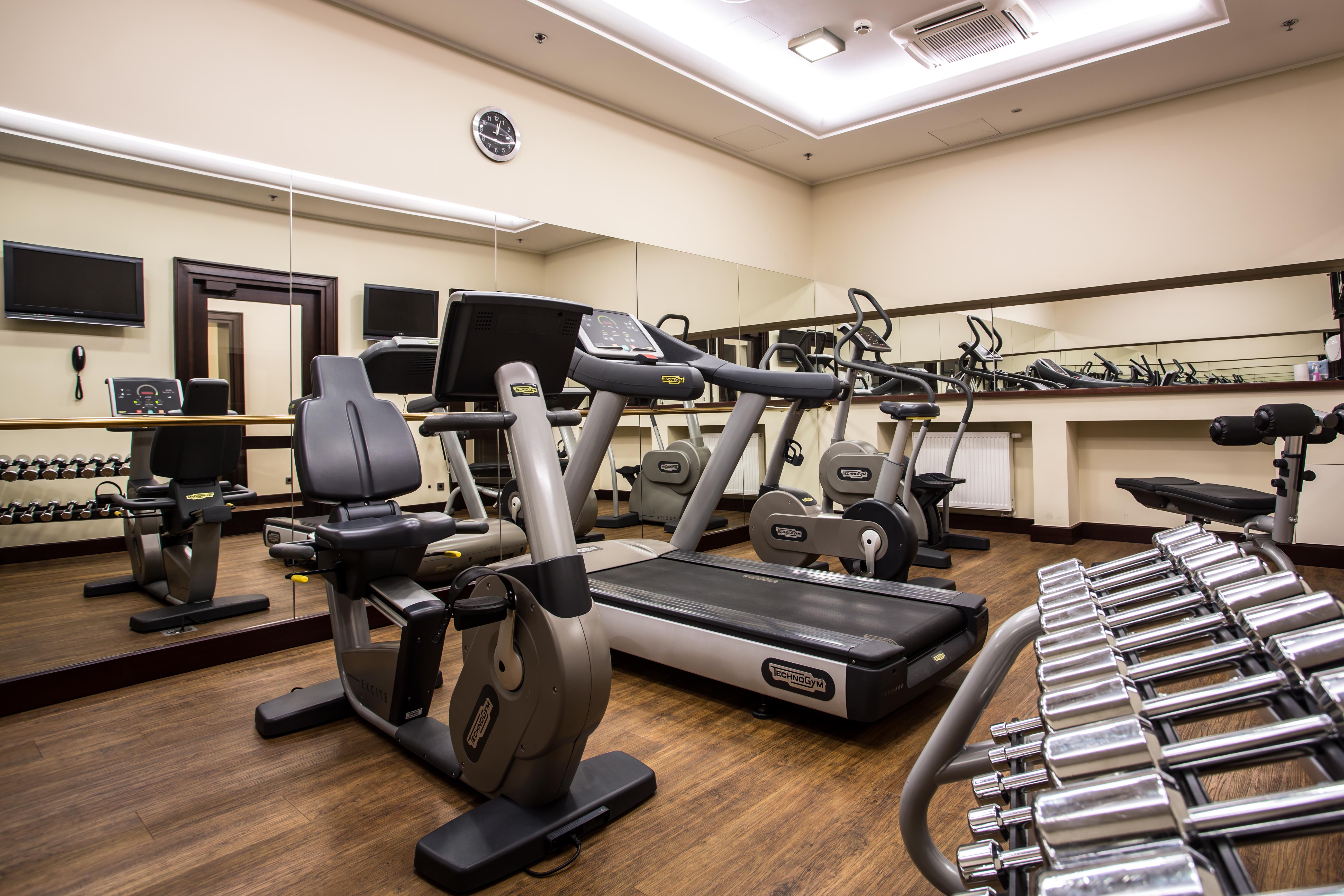 فندق راديسون بلو، غدانسك المظهر الخارجي الصورة The photo displays a small gym or fitness room. The room features various exercise equipment, including a treadmill, an elliptical machine, and a set of dumbbells arranged on a rack. There are mirrors on the wall, which help create a sense of space a