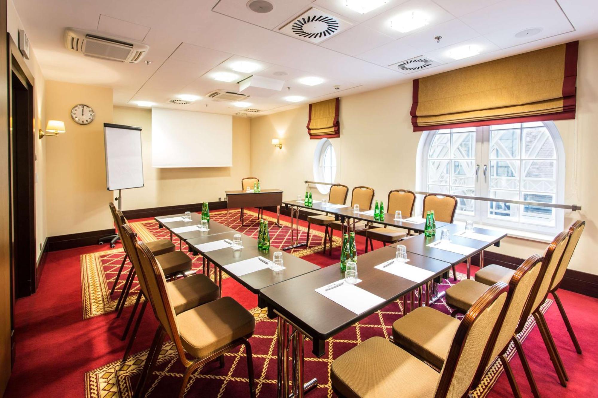 فندق راديسون بلو، غدانسك المظهر الخارجي الصورة The photo shows a conference room set up for a meeting. It features a large rectangular table surrounded by several chairs. On the table, there are bottles of water and paper notepads for participants. A flip chart is positioned at one side of the ro