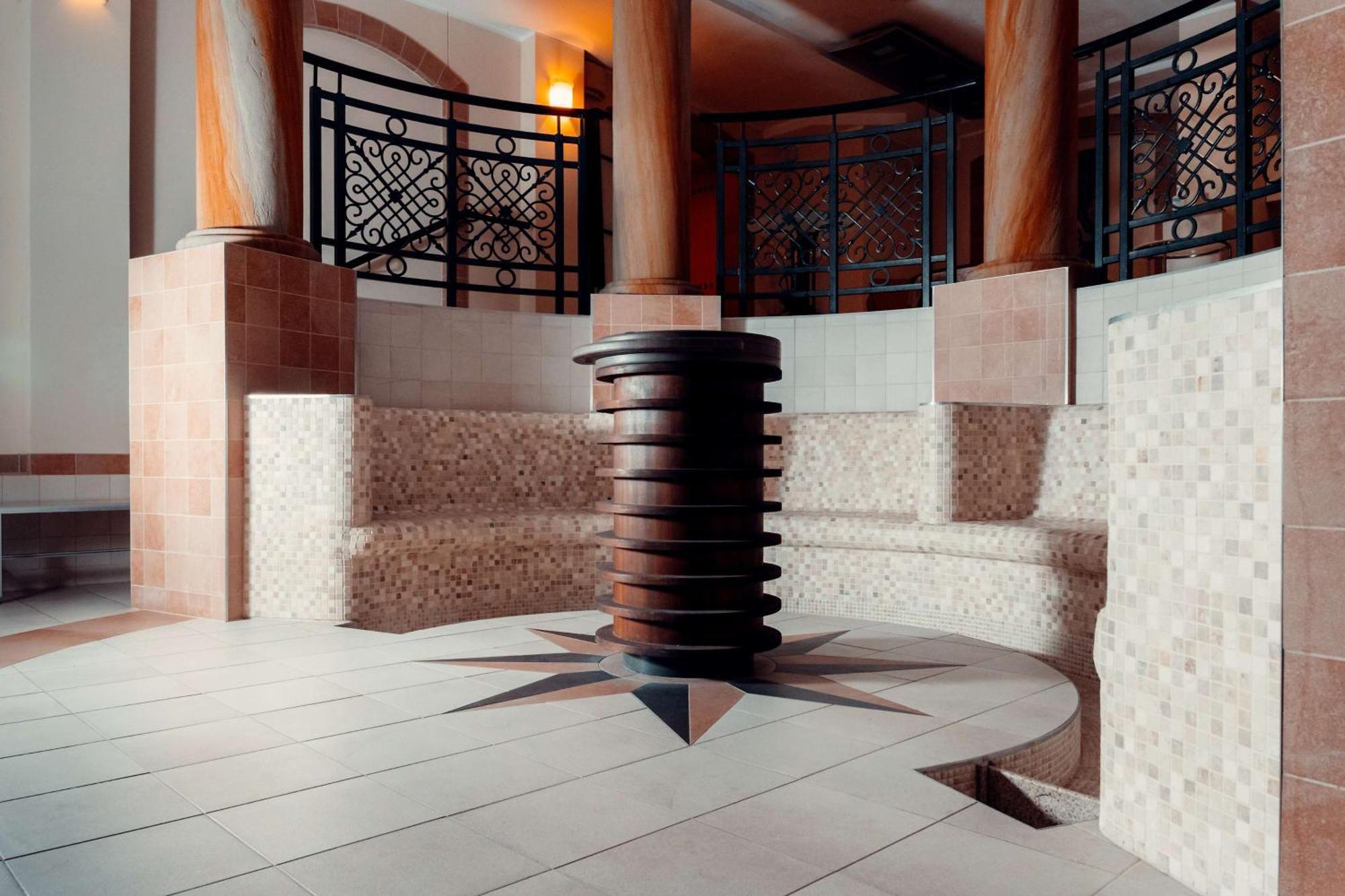 فندق راديسون بلو، غدانسك المظهر الخارجي الصورة The photo showcases a well-designed interior space, likely part of a spa or wellness center. In the center, there is a circular seating area made of tiled blocks arranged in a semicircular pattern. The floor features a star-shaped design with contras